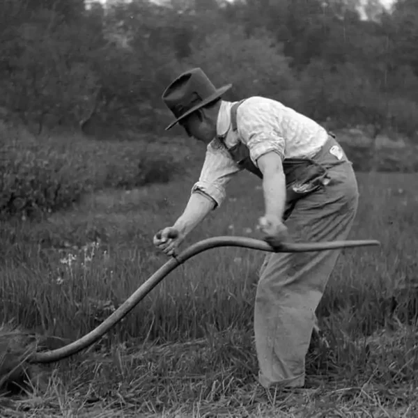 man mowing the grass with a scythe